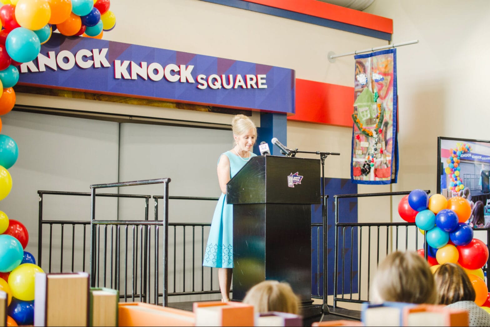 A woman speaking at a podium in Knock Knock Square
