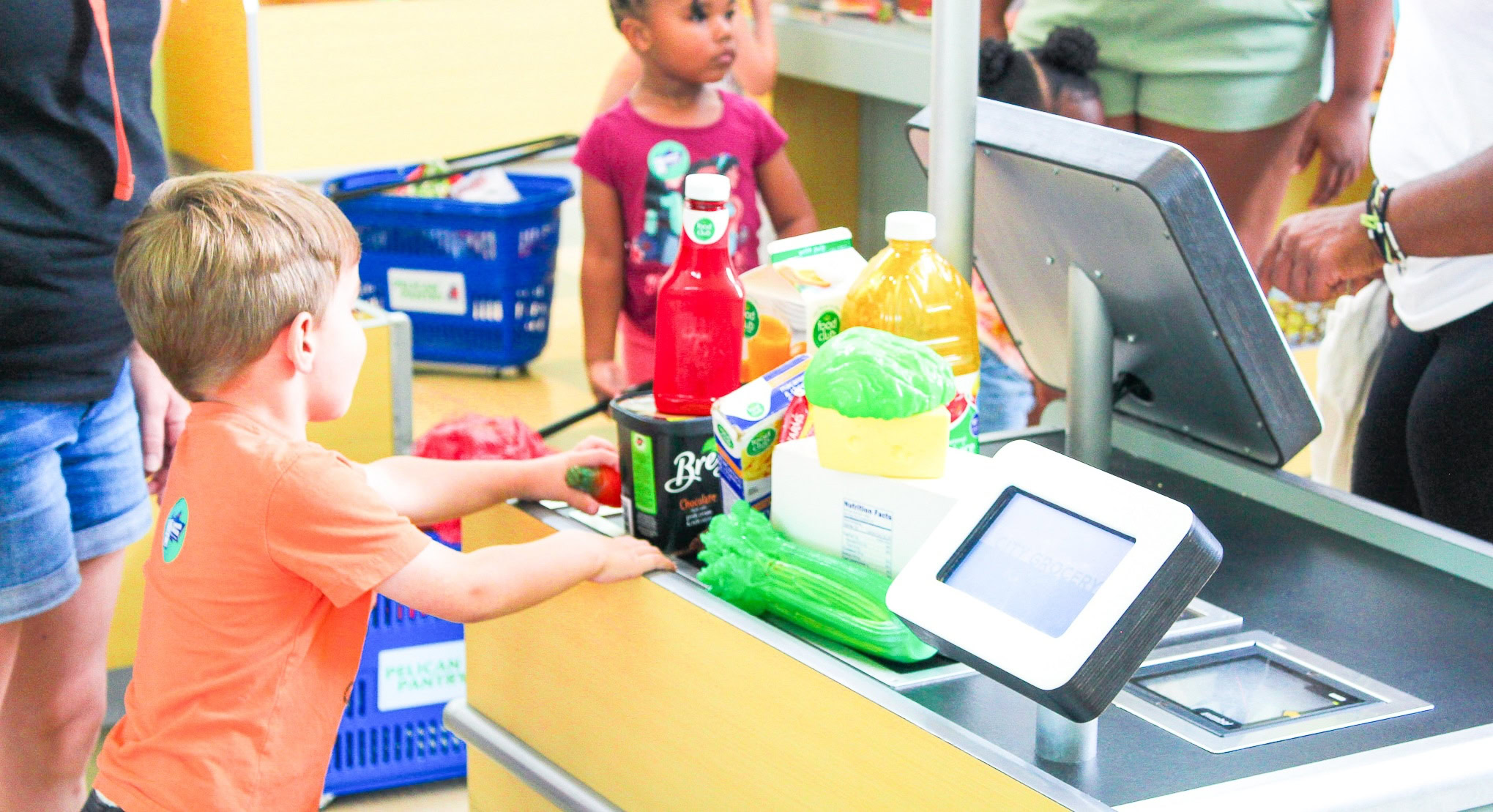 A boy in line with various items at a pretend grocery store register