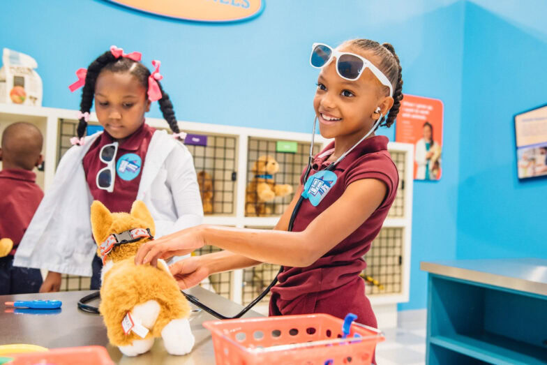 Two little girls playing vet with toy dogs in the Paws and