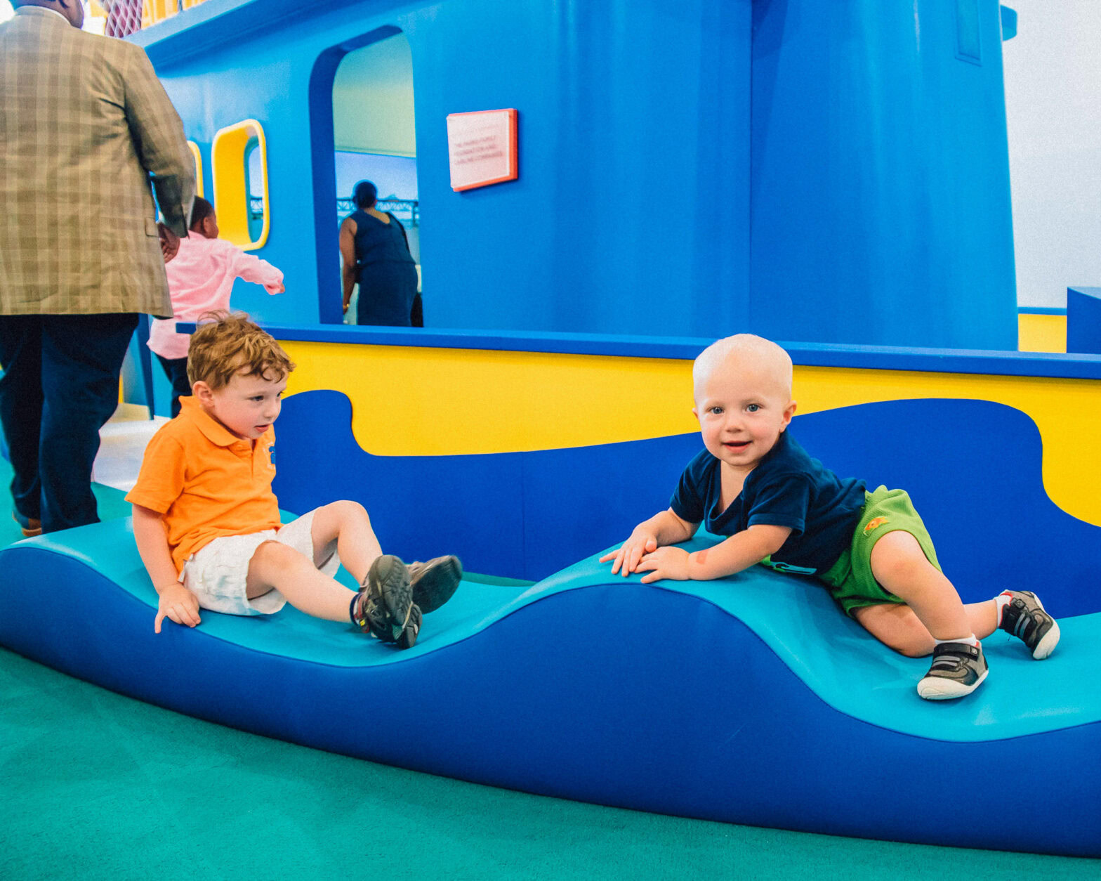 An image of two little boys playing on the blue play ship in the All Hands on Deck playing area.