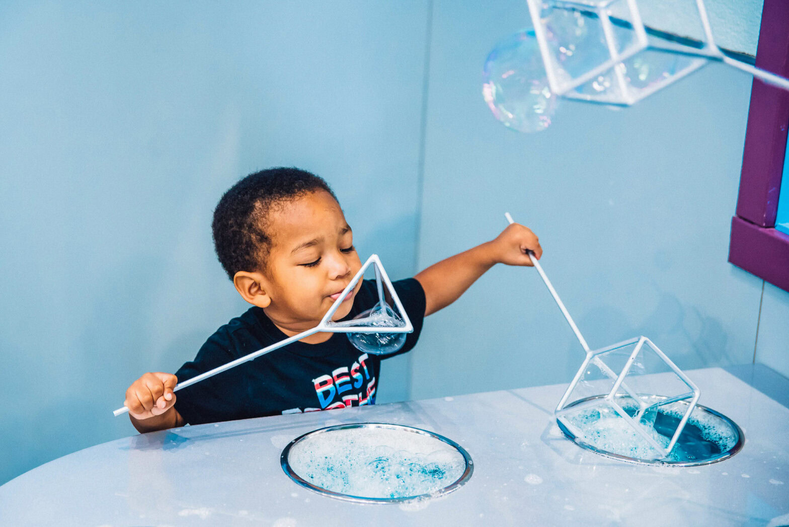 A little boy playing with two different bubble making tools
