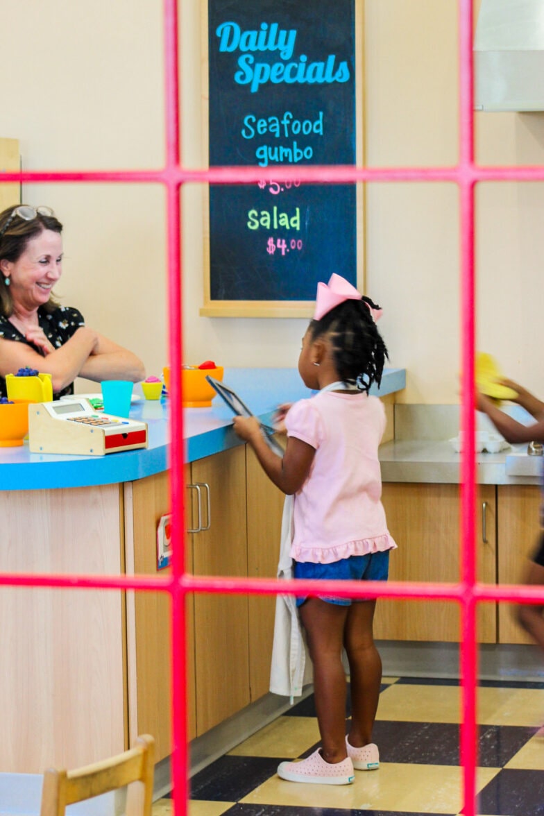 A little girl and a female adult playing in the toy cafe area