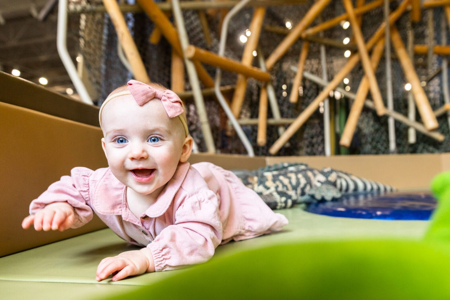 A little baby girl crawling along the soft mats in the crawbaby space.