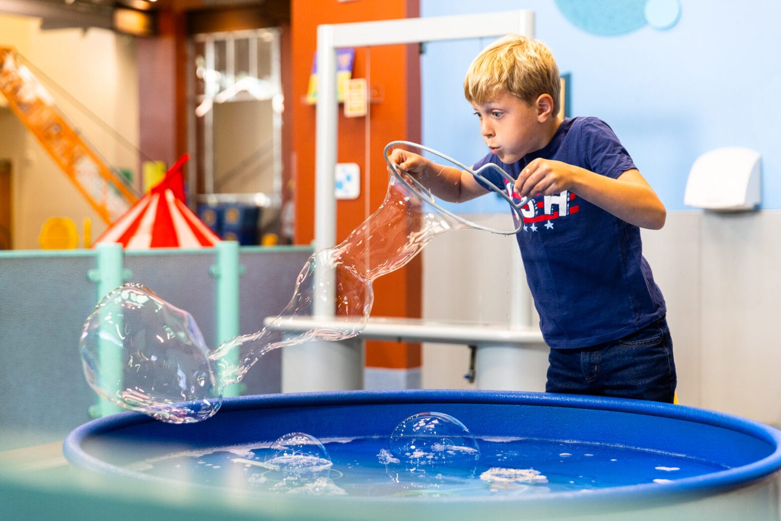 A little boy blowing bubbles in the bubble pool