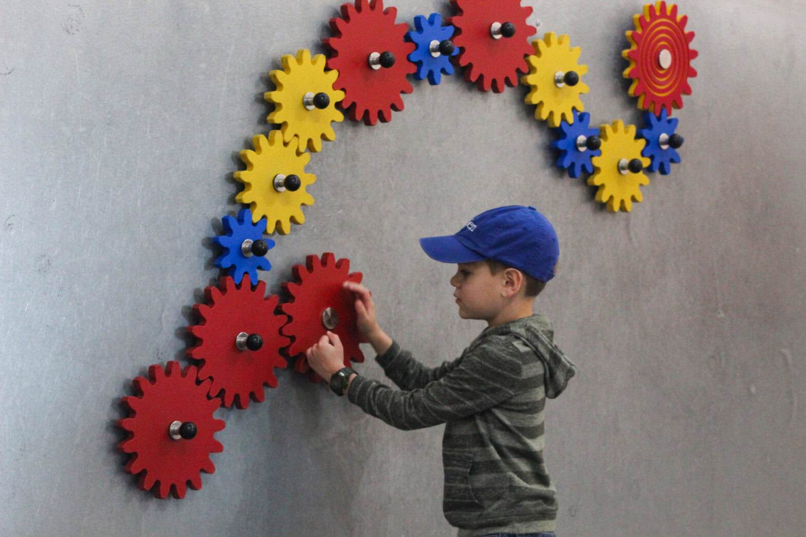 A little boy playing with toy gears on the magnet wall