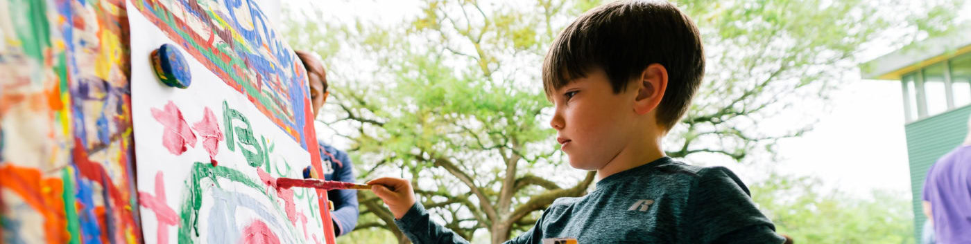 A young boy painting on an easel