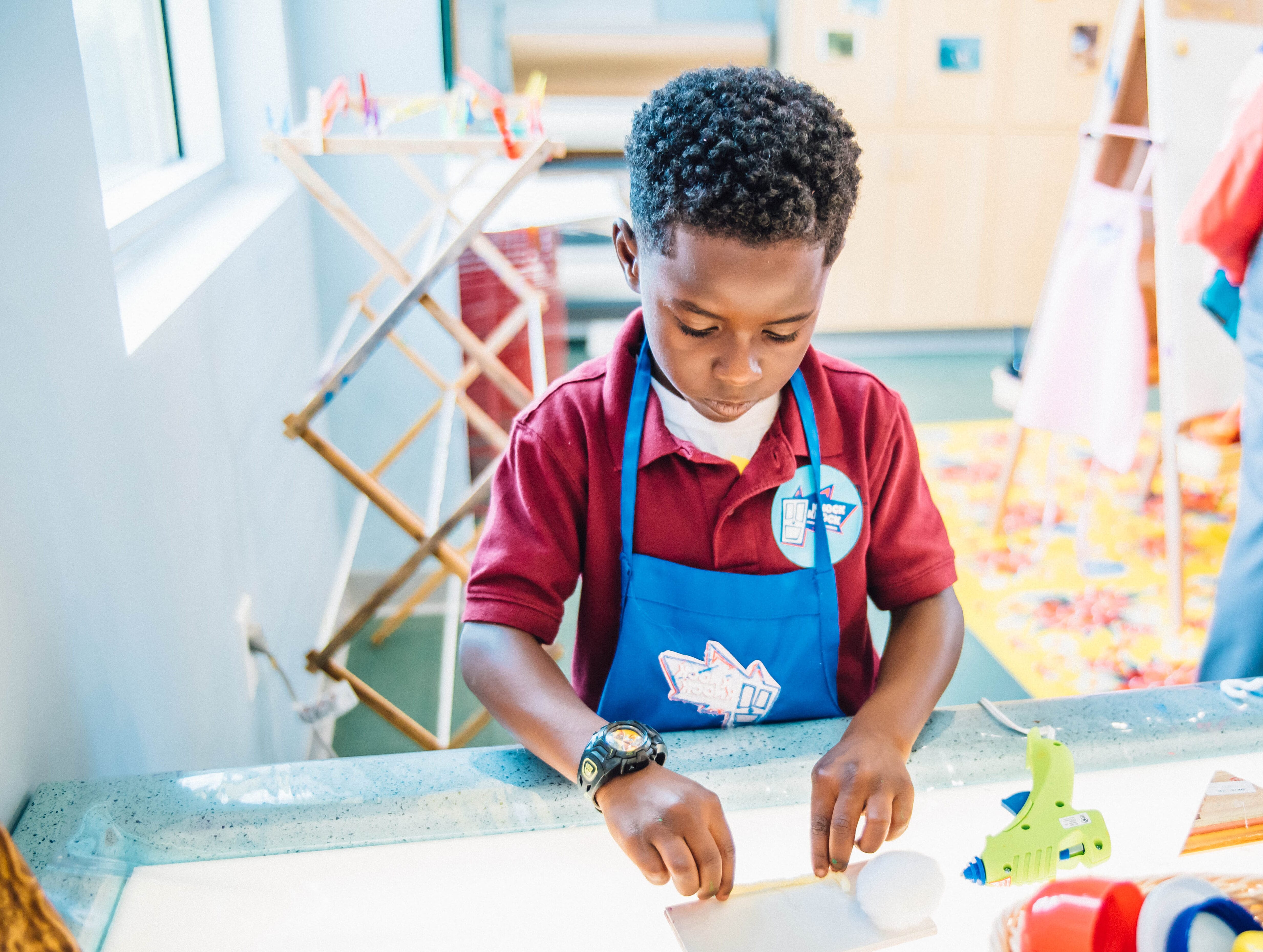 A young boy in a blue apron playing with art materials