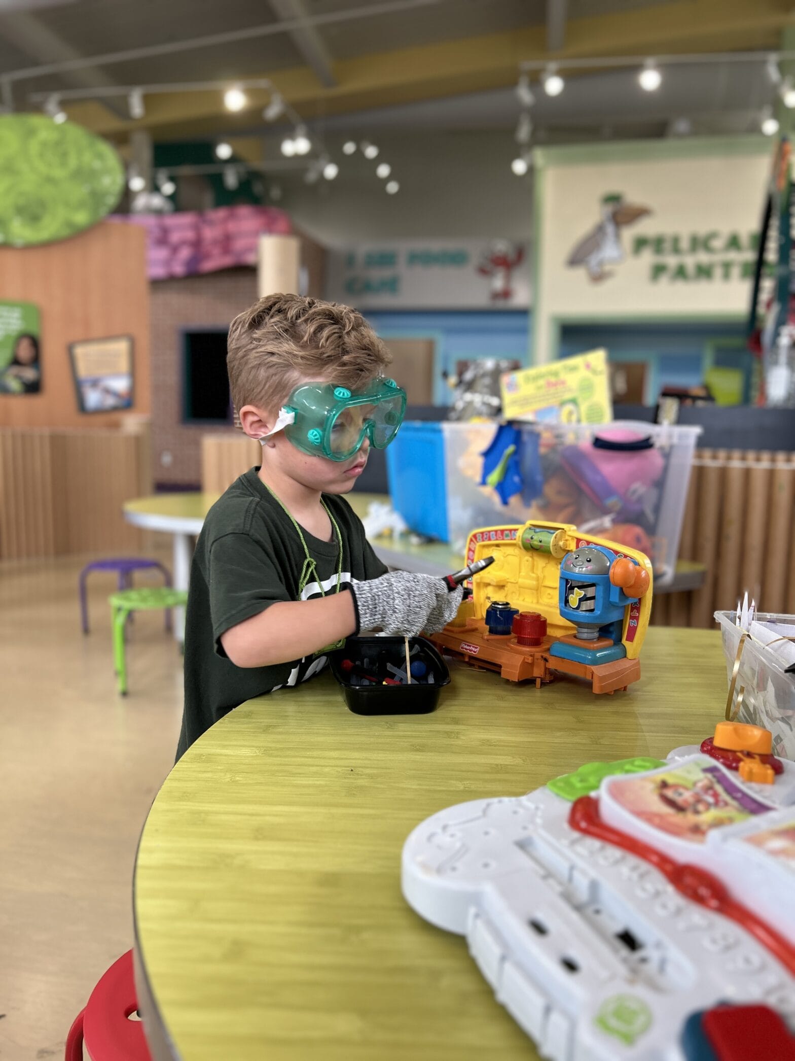 Young boy wearing goggles and gloves working on a toy.