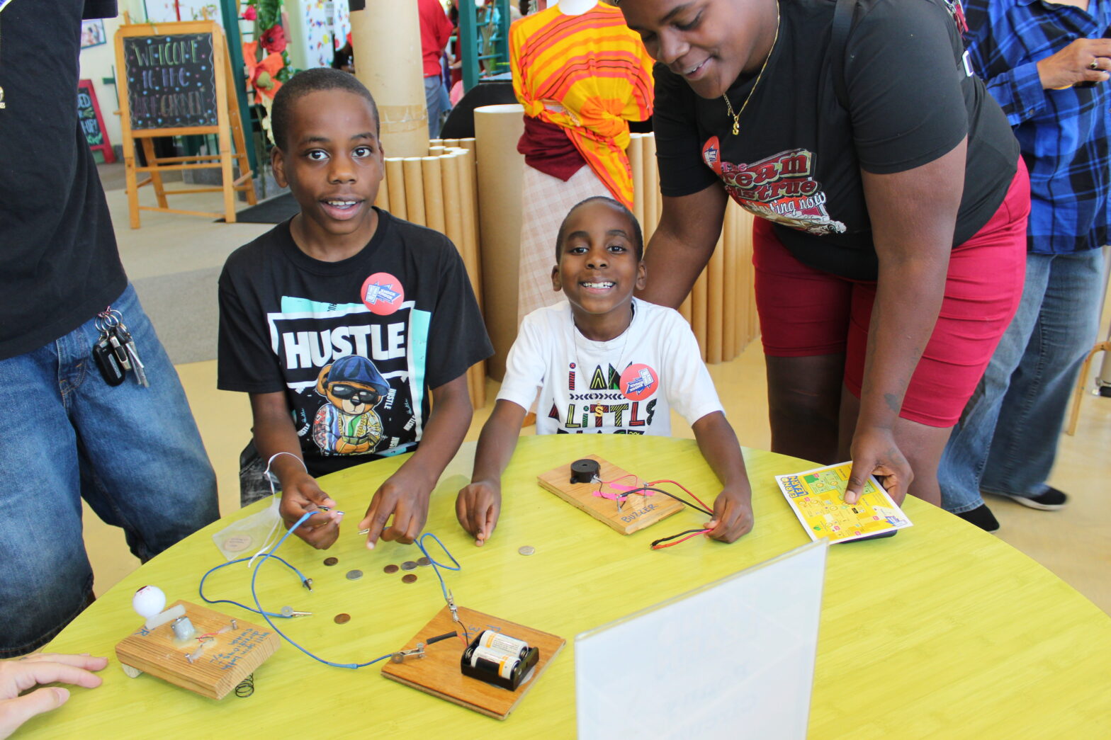 Two boys and their parents in the Maker Shop on Earn and Learn weekend participating in an activity with pennies and dimes.