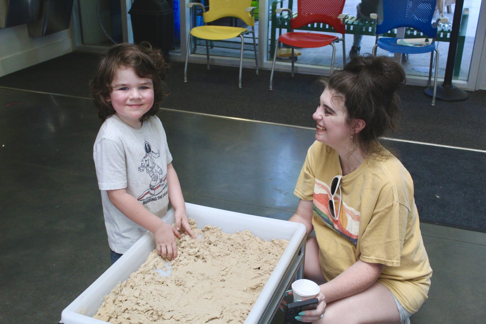 A child and mother play with sand play dough.