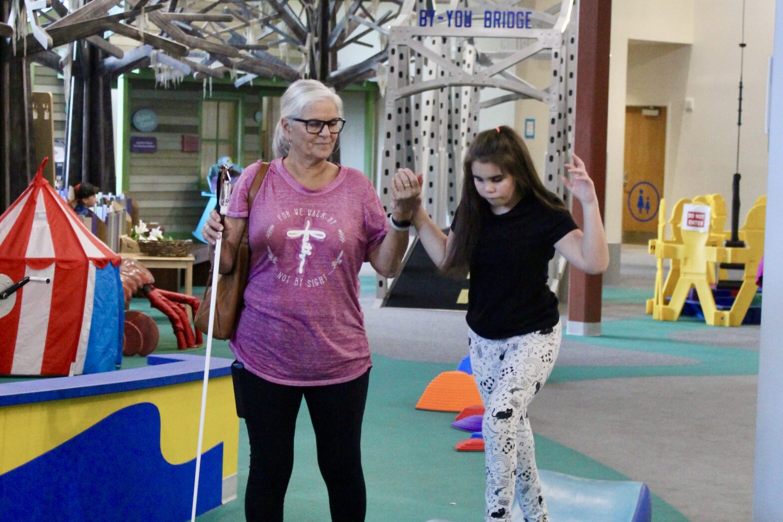 a girl and her grandmother watch across the gym mat.
