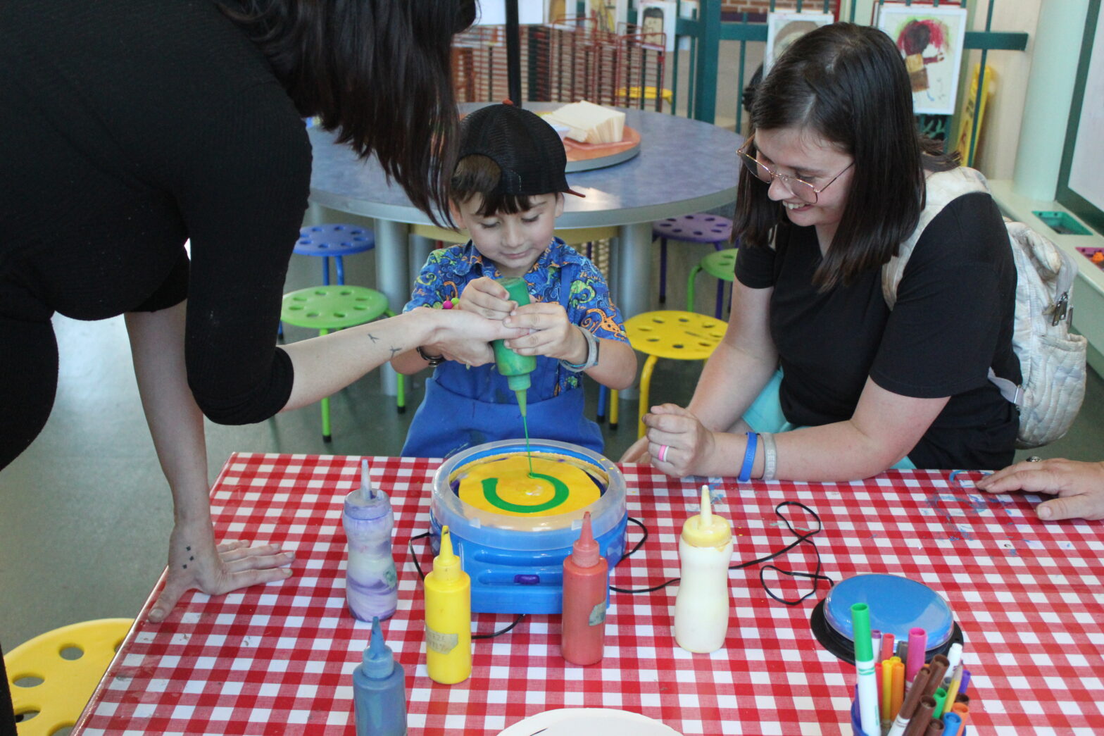 Boy plays with paint wheel with mother and Knock Knock employee.