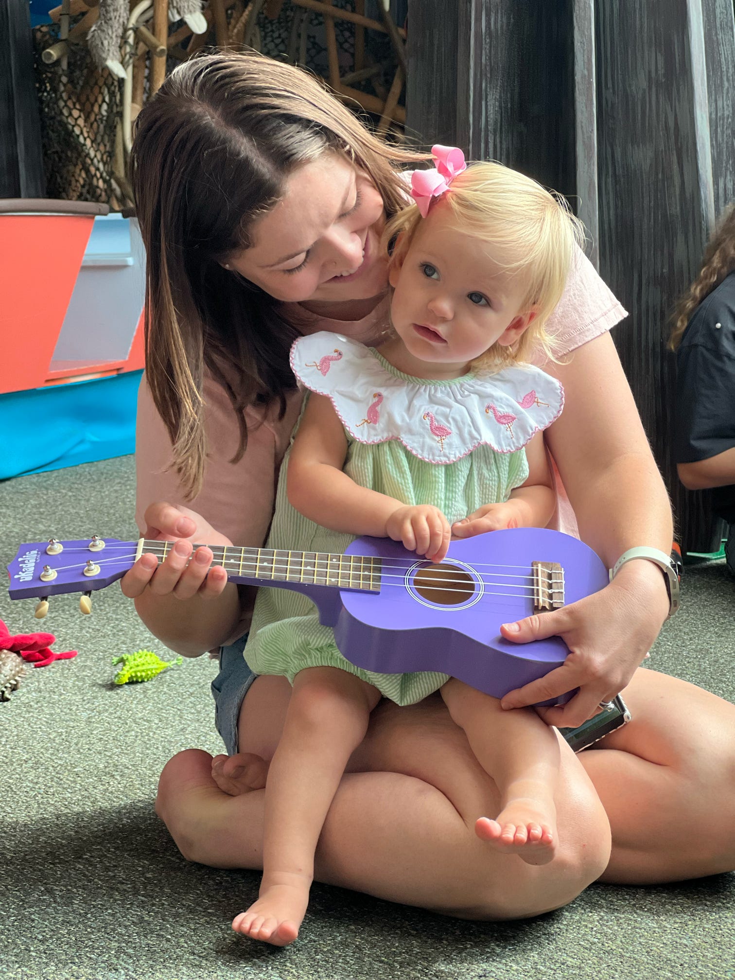 A mother and toddler play a ukulele