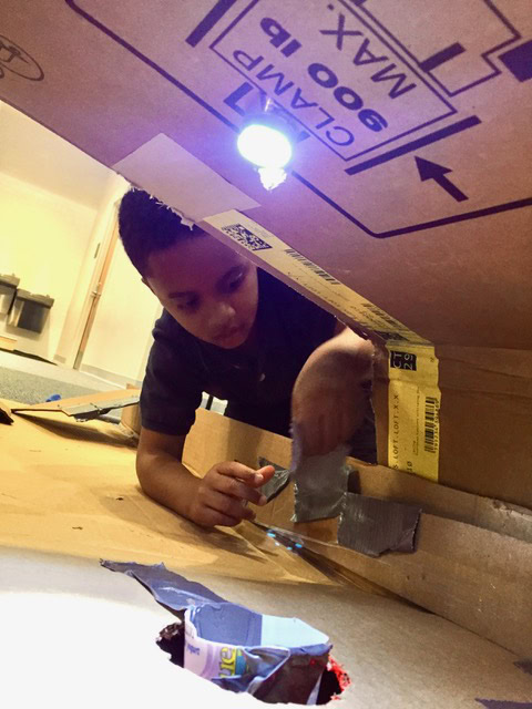 Child constructs a mini golf course using cardboard.