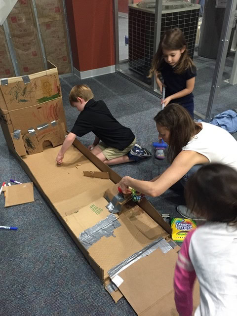 Children construct mini golf course using cardboard.